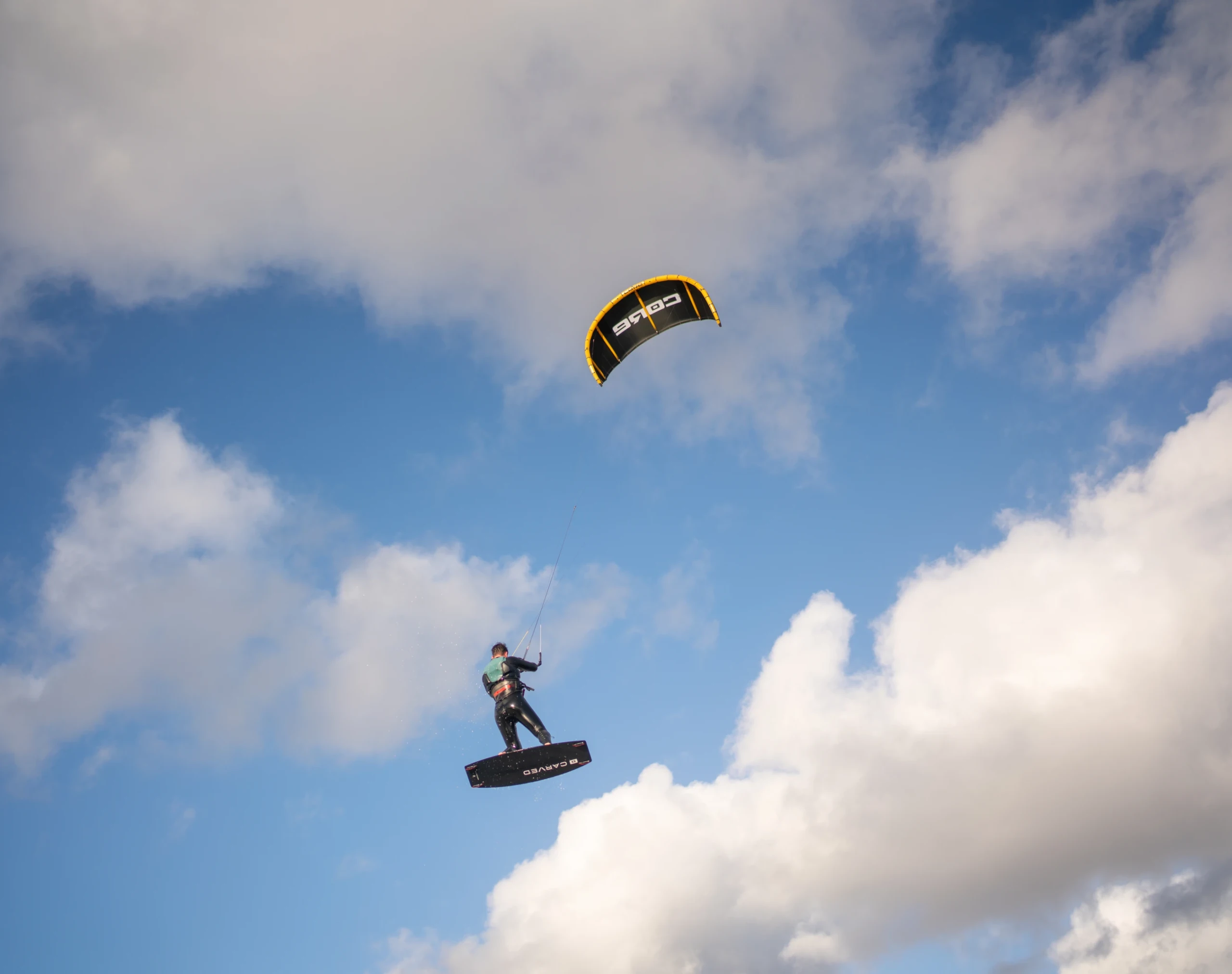 Een kitesurfer die door de lucht vliegt