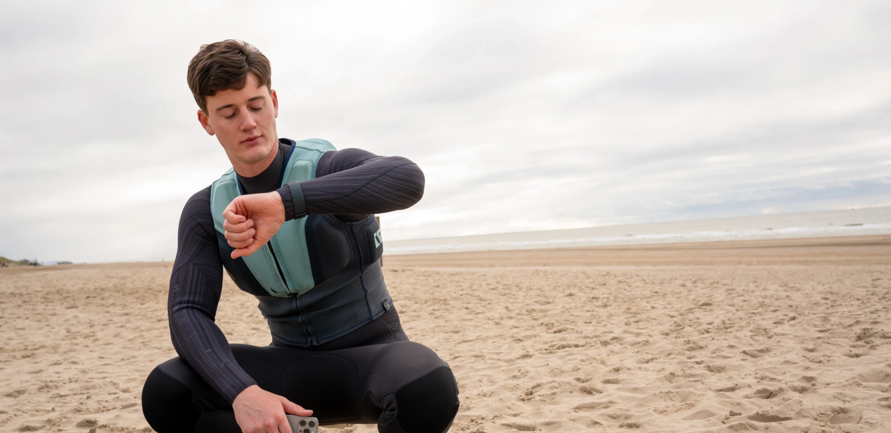 Kitesurfer bekijkt zijn smartwatch op het strand